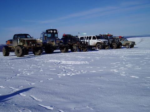 2000 Ford E350 - A collection of custom off-road vehicles are lined up in a snow-covered field.