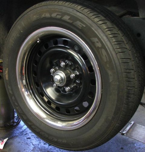 1985 Ford Crown Victoria LTD - Close-up of a black steel wheel with a chrome trim ring and a tire with visible text.