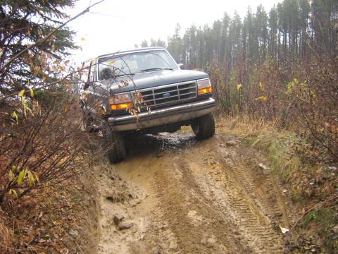 1995 Ford Bronco - Ford Bronco tackles a challenging muddy track during an off-road excursion.