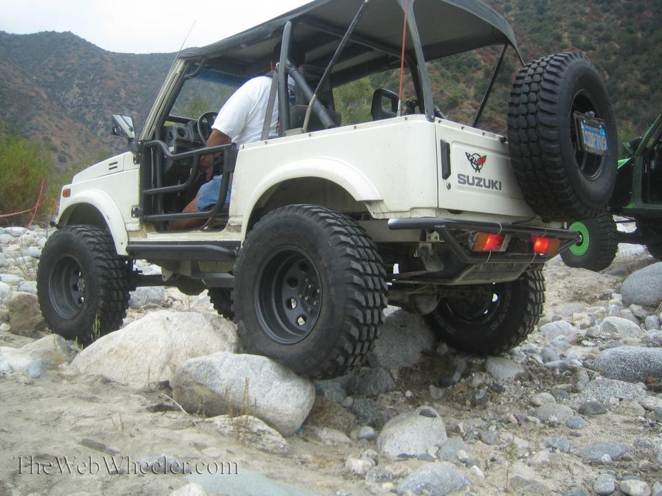 White 1987 Suzuki Samurai with off-road tires navigating rocky terrain