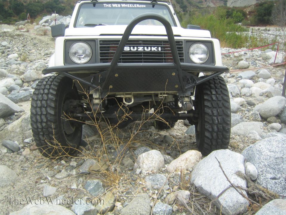 White 1987 Suzuki Samurai front view with aftermarket bumper and off-road tires