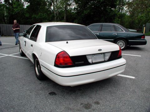 1998 Ford Crown Victoria - A white 1998 Ford Crown Victoria is parked in a lot, with another vehicle visible behind it.