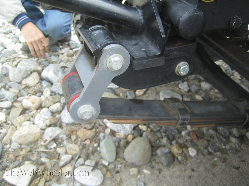 Vehicle suspension linkage with red and black bushings attached to leaf springs
