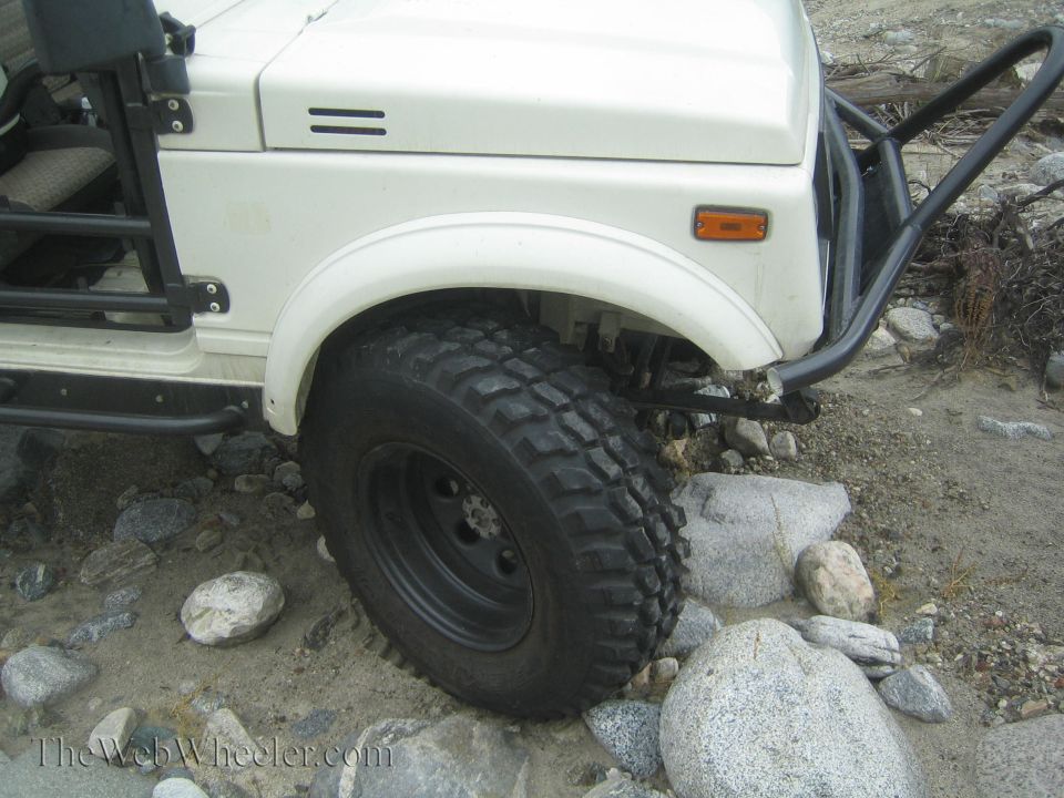 White 1987 Suzuki Samurai front fender, tire, and aftermarket bumper off-road