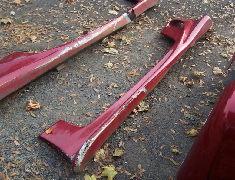 Red car body kit side skirts and fender parts on the ground