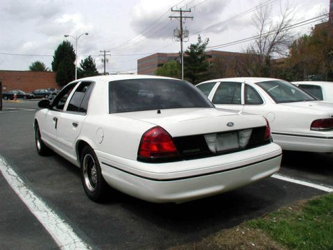 1998 Ford Crown Victoria - Rear view of a white 1998 Ford Crown Victoria parked in a lot next to another similar vehicle.