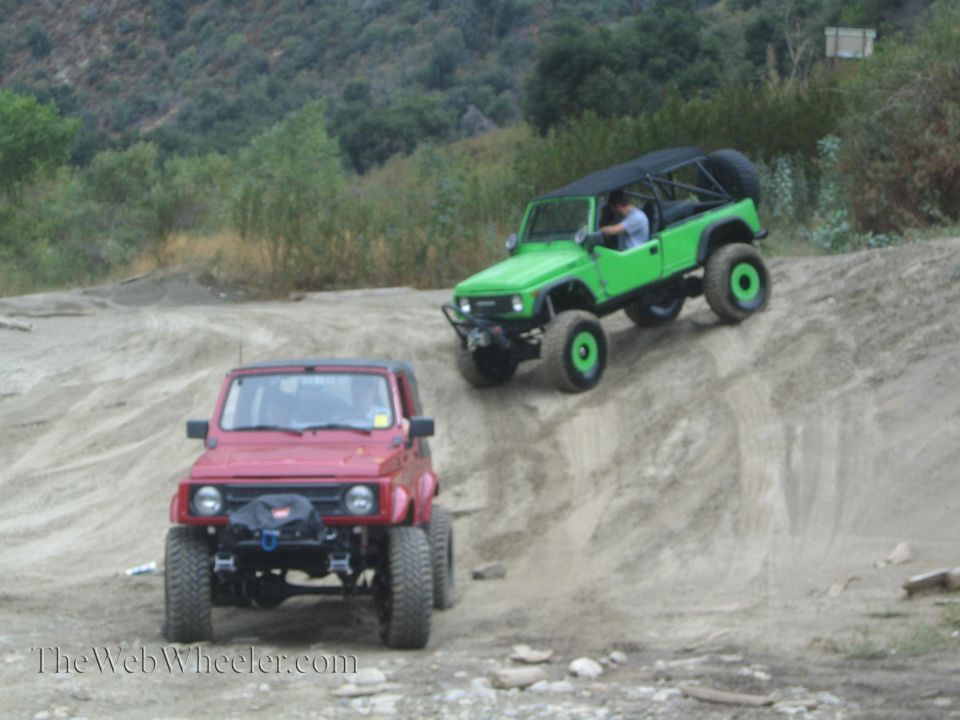 Red Suzuki Samurai in front, green one climbing hill behind it. Both have off-road tires