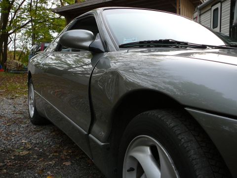 1996 Ford Probe - The side profile of a gray coupe is visible, with a focus on the front wheel well and door panel.
