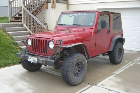1998 Jeep TJ - This red Jeep Wrangler features a tan soft top and is viewed from the front 3/4 angle.