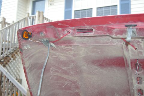 1998 Jeep TJ - Underside of a red car hood with an amber marker light and exposed wiring.
