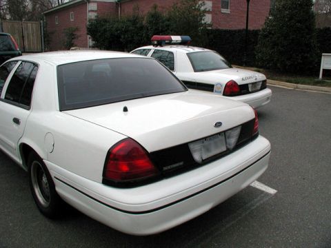 1998 Ford Crown Victoria - Two white police cars are parked in a lot. The foreground car is a 1998 Ford Crown Victoria.