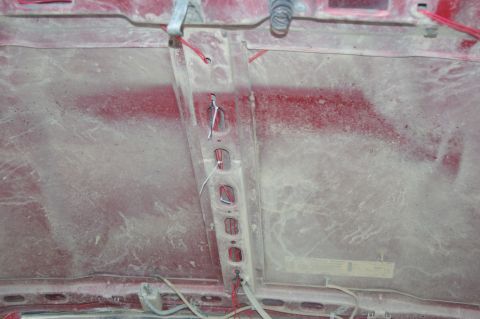 1998 Jeep TJ - The underside of a red vehicle hood shows wiring and a central support structure, covered in dust.