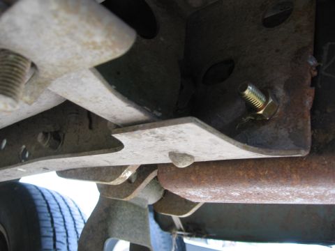1974 Ford F-100 - The underside of a vehicle shows rusted metal components and a tire in the lower left corner.