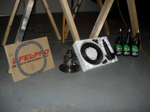 1995 Ford Bronco - Differential parts and gear oil laid out on a concrete floor with sawhorses in the background.