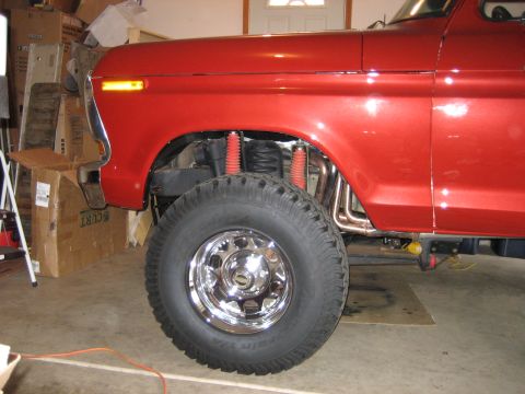 1979 Ford Bronco - Close-up of a red 1978 Ford Bronco's front fender, wheel, and suspension.