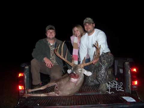1996 Ford F-150 - Three hunters pose with a large buck in the bed of a pickup truck at night.