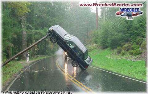 1996 Ford F-150 - A car is precariously balanced on a pole after an apparent accident on a rainy day.