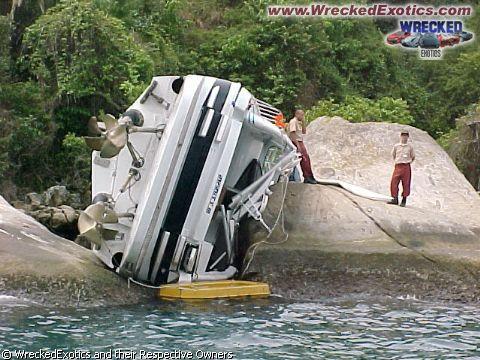 1996 Ford F-150 - A boat has run aground and is resting on its side on large rocks near the water's edge.