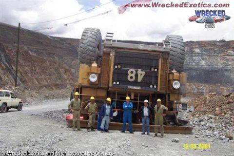 1996 Ford F-150 - An overturned mining dump truck lies on its side in a quarry, with several workers observing the scene.
