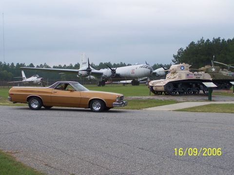 1973 Ford Ranchero - A 1973 Ford Ranchero is parked at an outdoor museum with vintage aircraft and military tanks.
