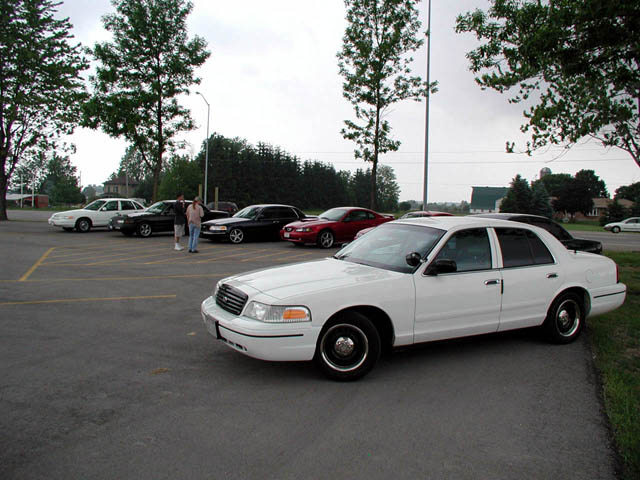 White Ford Crown Victoria sedan parked in lot, 3/4 front view