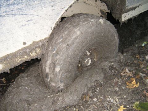 1990 Ford Bronco - A vehicle's tire and fender are heavily caked in mud, suggesting it is stuck in difficult terrain.