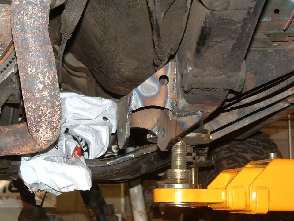 underneath vehicle frame with new metal brackets welded on, supported by a yellow jack
