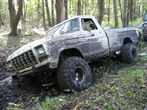 1990 Ford Bronco - Mud-covered 1979 Ford F-150 is stuck off-road, with another vehicle visible in the background.