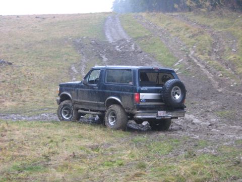 1995 Ford Bronco - This 1995 Ford Bronco is navigating a challenging off-road trail with muddy terrain.