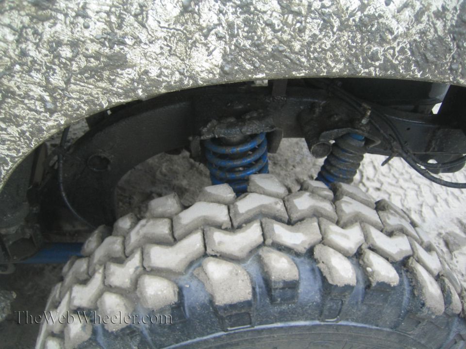 Mud-covered tire and blue suspension spring on an off-road vehicle