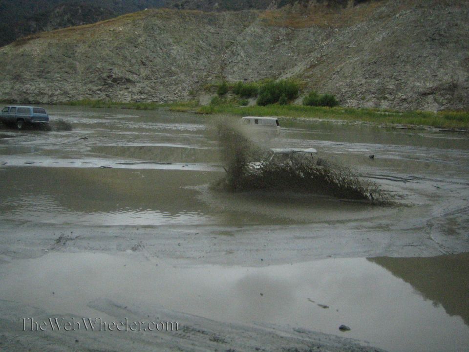 White off-road vehicle churning mud in a watery landscape