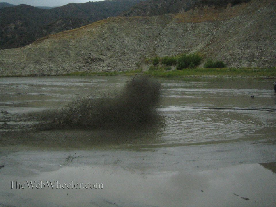 Muddy water spraying from a vehicle in a shallow body of water