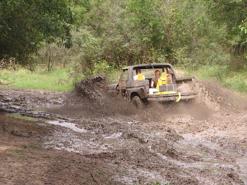 Truck driving through a mud pit with people inside