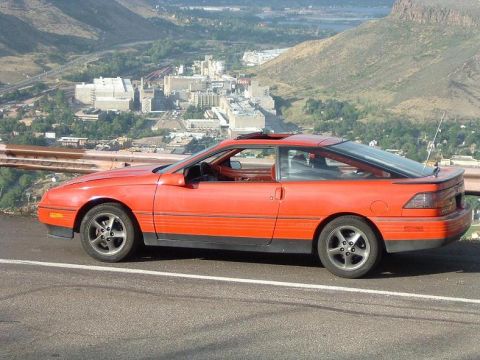 1989 Ford Probe - This 1989 Ford Probe is seen from the side with a city and mountains in the background.