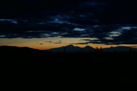 2003 Jeep TJ - Mountain range silhouetted against a dark sky with orange and blue clouds at dusk.