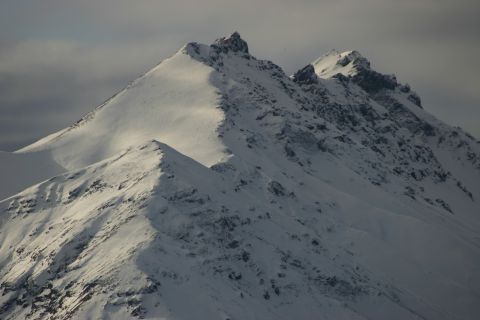 2003 Jeep TJ - The terrain of snow-covered mountains is visible under a dramatic sky.