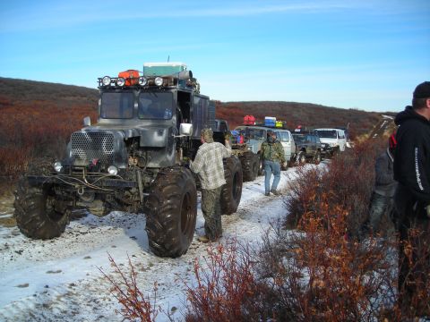 2003 Jeep TJ - Multiple off-road vehicles, including a large truck and SUVs, travel in a convoy on a snowy path.