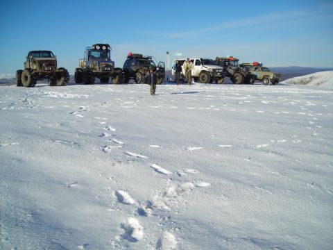 2003 Jeep TJ - A group of vehicles are parked in a vast, snow-covered area under a bright blue sky.