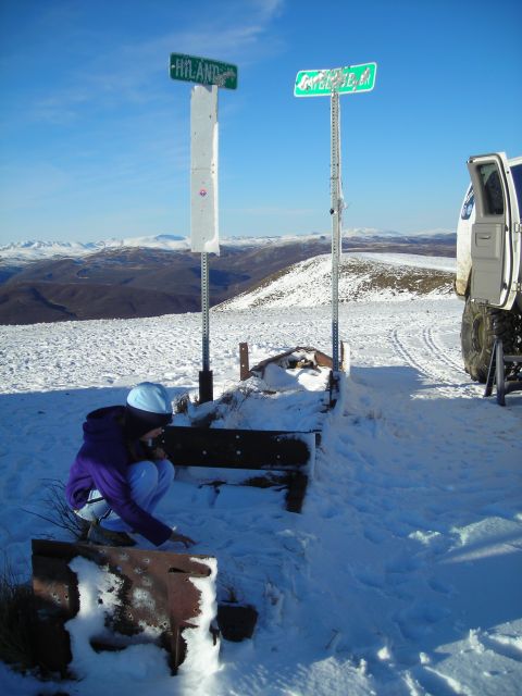 2003 Jeep TJ - A white SUV is parked on a snowy mountain road, its door open, near two street signs.