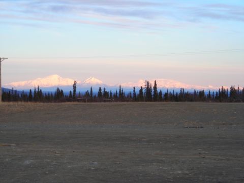 2003 Jeep TJ - Distant snow-covered mountains are seen at sunrise behind a dark forest and open field.