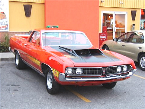 1967 Ford Ranchero - This red 1969 Ford Ranchero features a prominent black hood scoop and a yellow stripe along its side.