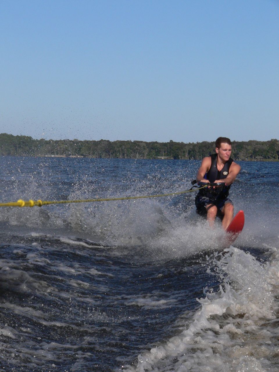 Man water skiing on a lake, pulled by a boat. Water is splashing