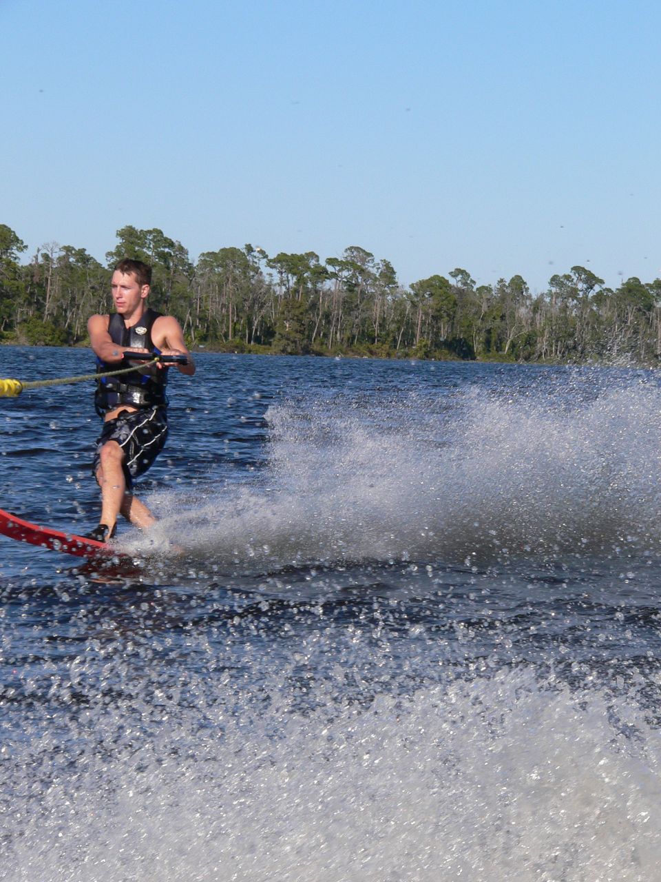 Man water skiing behind a boat, creating a large spray