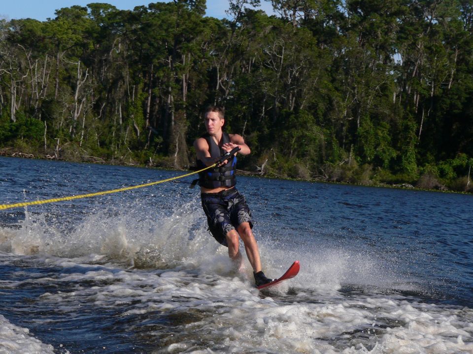Water skier on a red slalom ski holding a yellow tow rope behind a boat