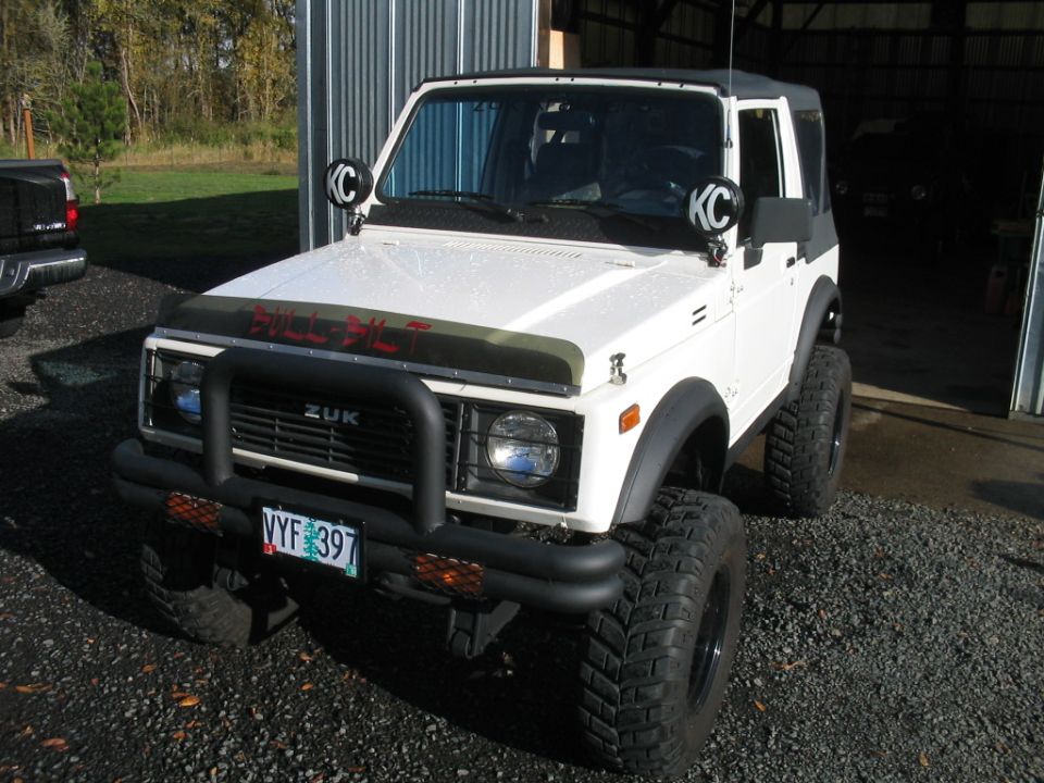 Lifted white Suzuki Samurai with brush guard, KC lights and BULL-BILT hood lettering