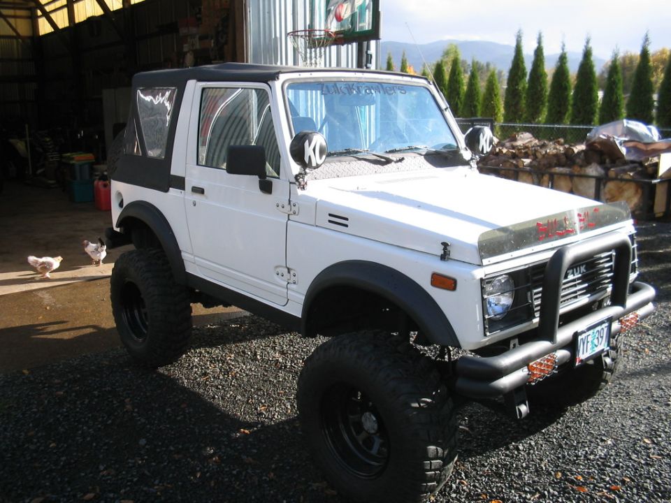 White 1987 Suzuki Samurai with large tires and a soft top