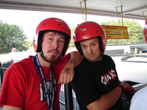 1994 Ford Probe - Two men wearing red helmets pose for a photo at an outdoor track, possibly a go-karting venue.