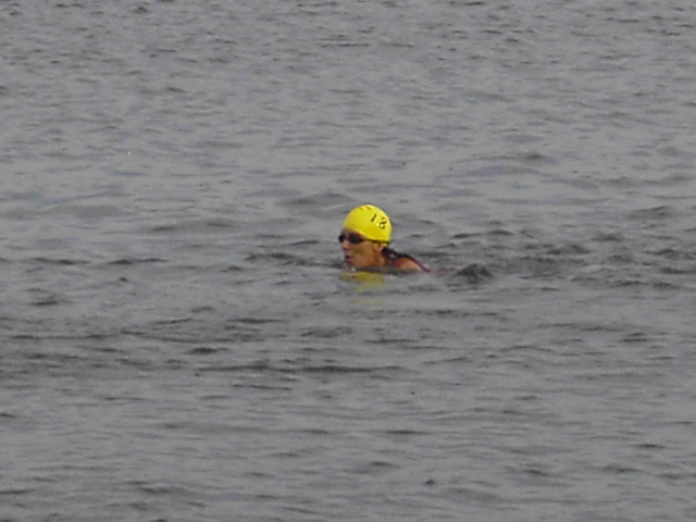 Swimmer in yellow cap and goggles in open gray water