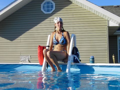 1991 Ford Bronco - A woman relaxes on a pool ladder next to a house on a sunny day.