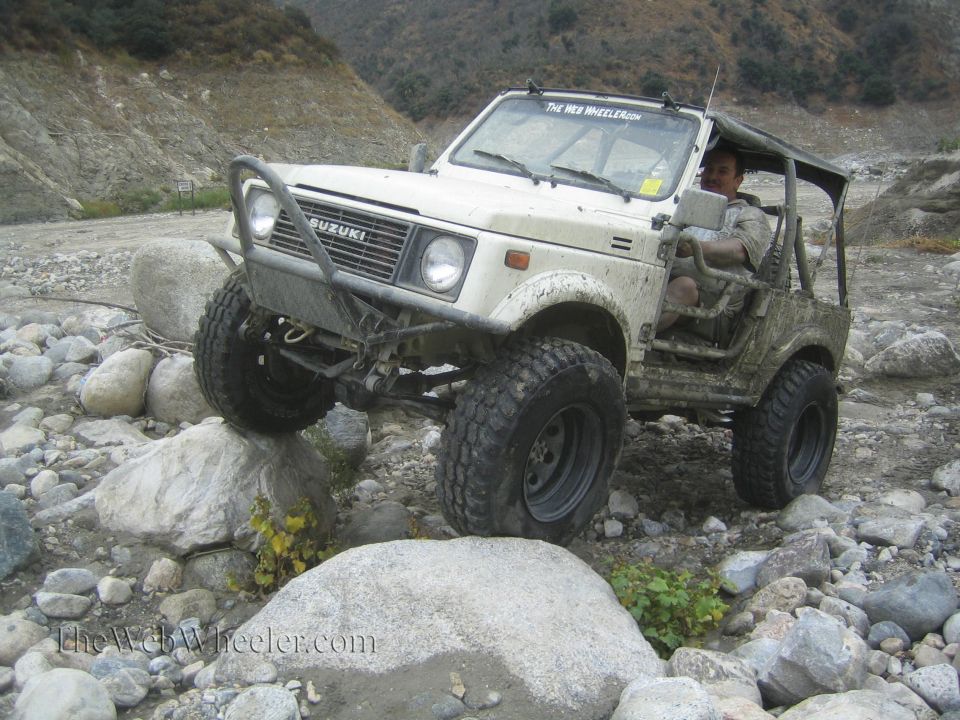 White 1987 Suzuki Samurai navigating rocky terrain